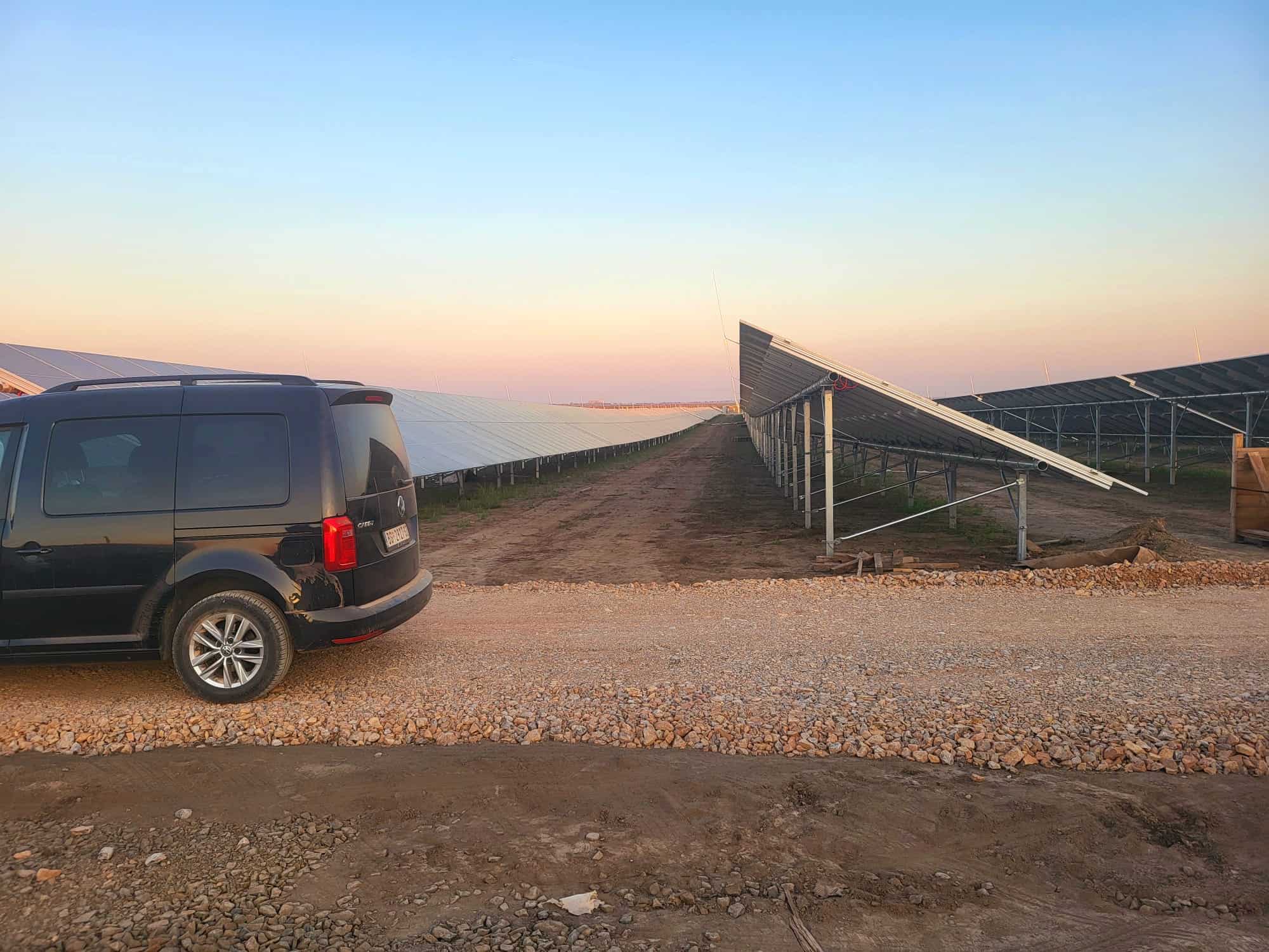 Solar power farm with solar panels and vehicle in the foreground.