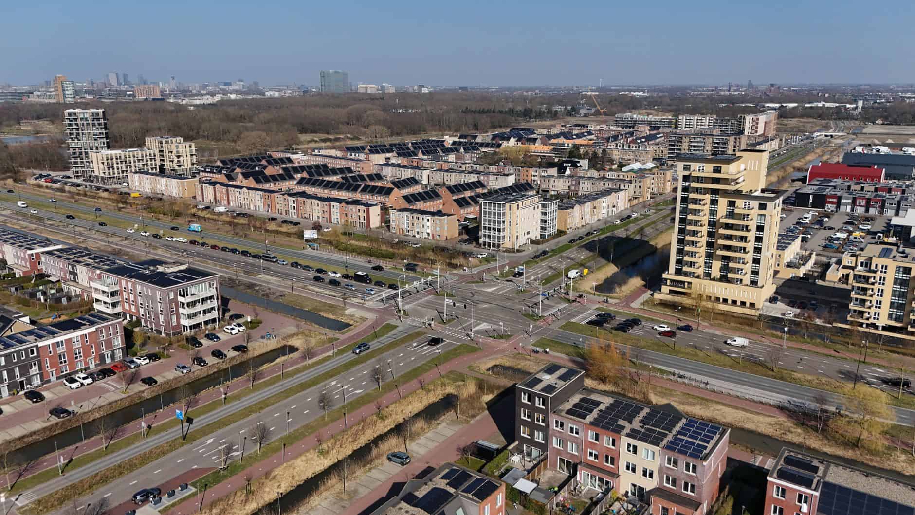 Aerial view of a city with solar panels on rooftops and busy roads.