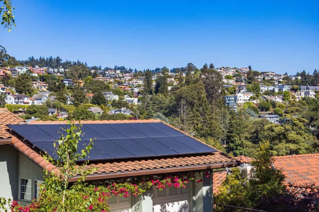 Solar panels installed on a house roof in a hilly neighborhood.