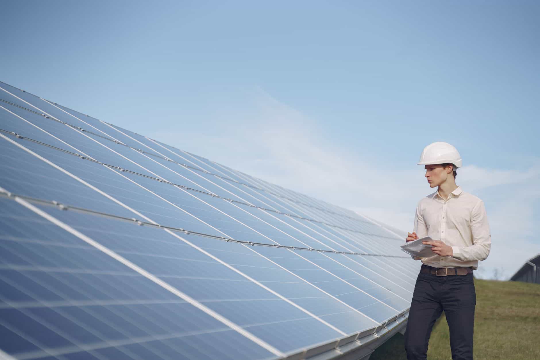 Female engineer inspecting solar panels at a solar farm.