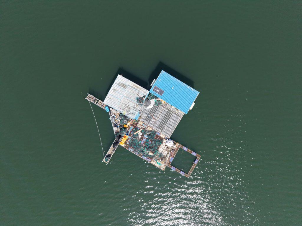 Aerial view of a solar-powered floating platform on water with solar panels and structures.
