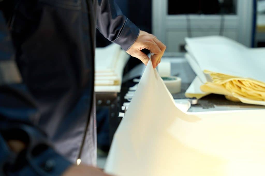 An industrial worker manages large sheets in a manufacturing setting, focusing on precision and quality.