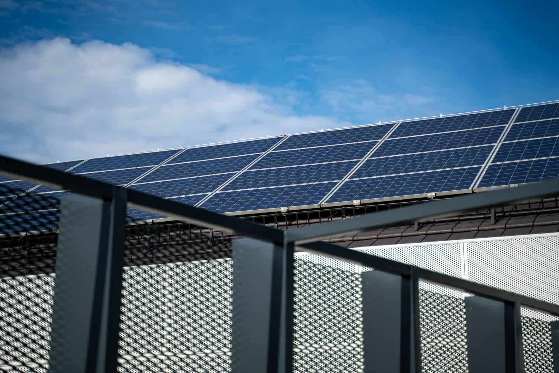 Solar panels installed on a building roof under a blue sky.