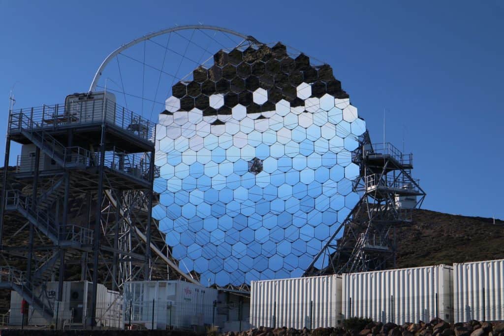 Futuristic reflective structure with hexagonal mirrors under a clear blue sky. Modern design.