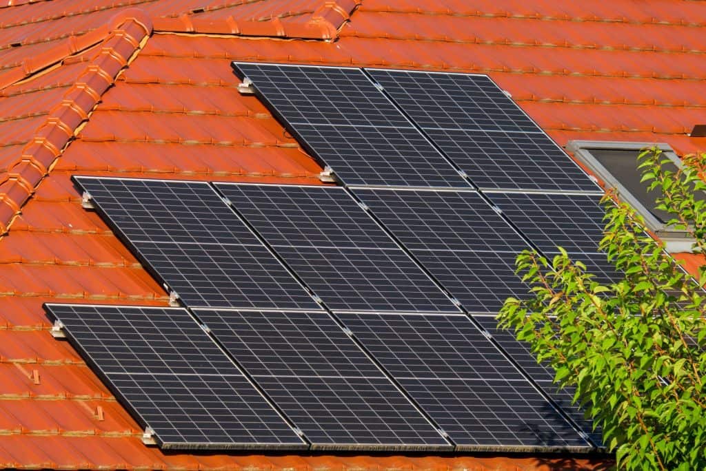 Solar panels installed on a red tiled roof for renewable energy.