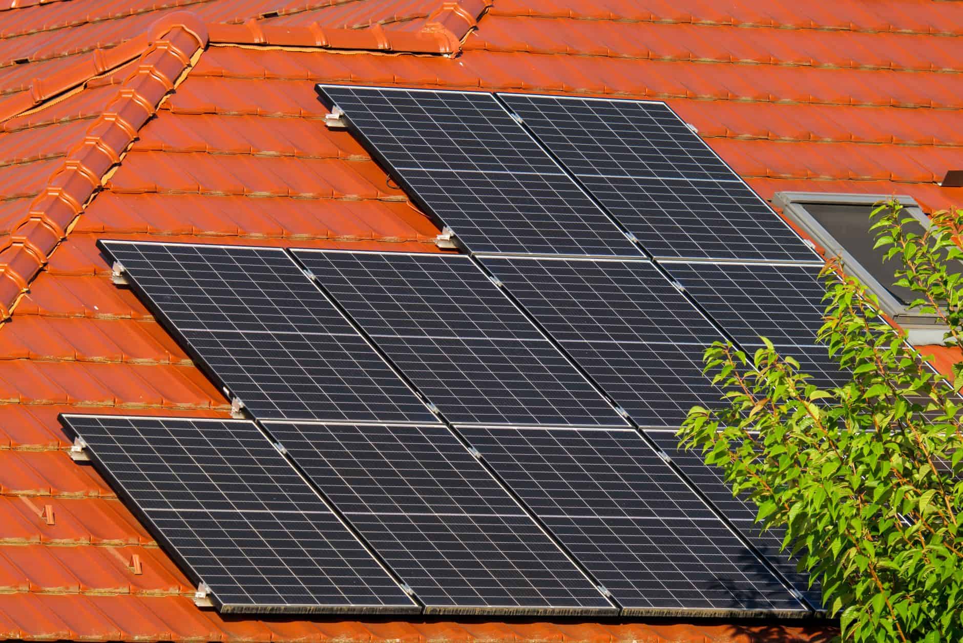 Solar panels installed on a red tiled roof for renewable energy.