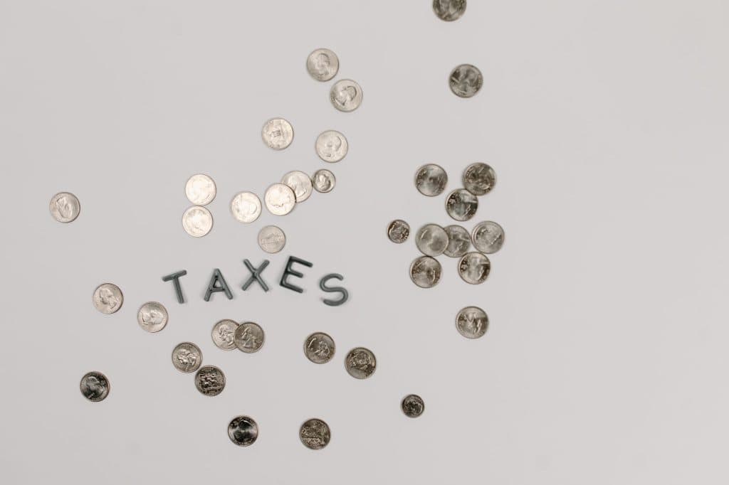 Coins scattered around the word 'TAXES' on a white background.