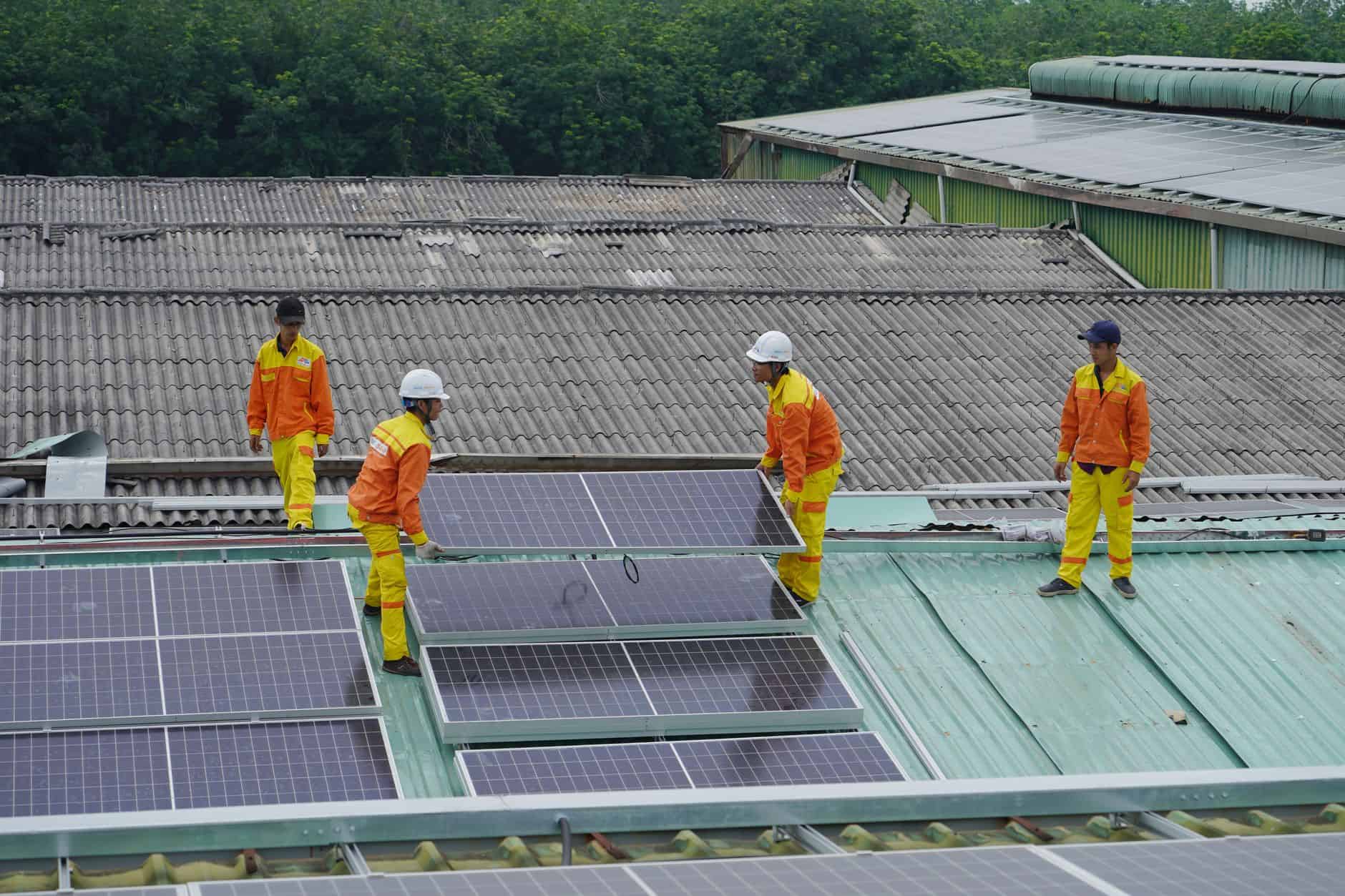 Arbeiter installieren Solarpaneele auf einem Dach zur Erzeugung erneuerbarer Energie.