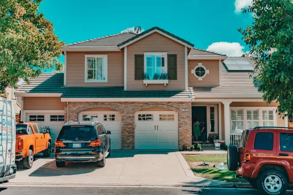 Charming suburban house with parked cars and vibrant summer setting.
