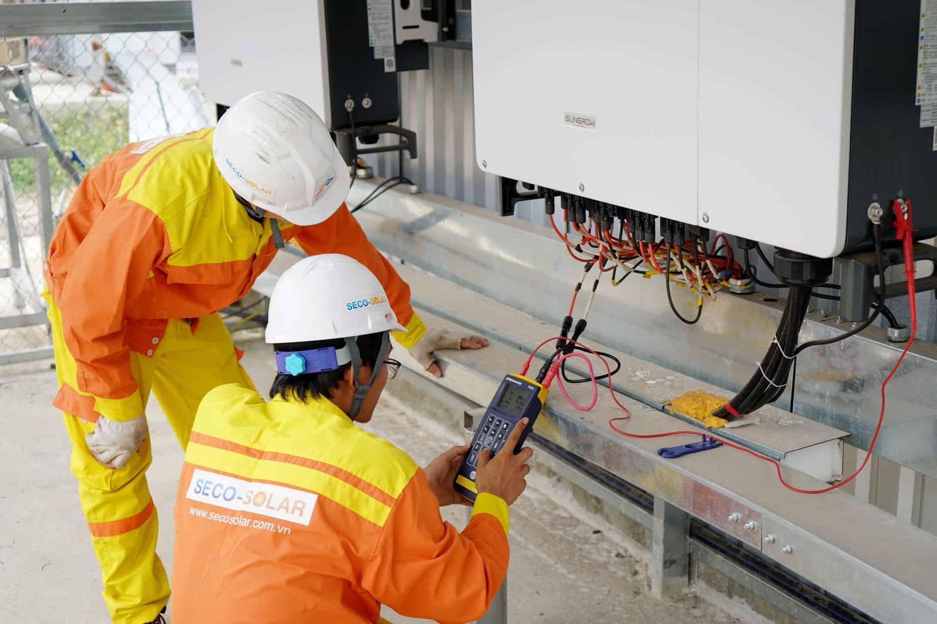 Solar panel technicians inspecting solar power system with testing equipment.
