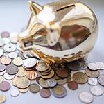A golden piggy bank surrounded by assorted coins, symbolizing savings and wealth.